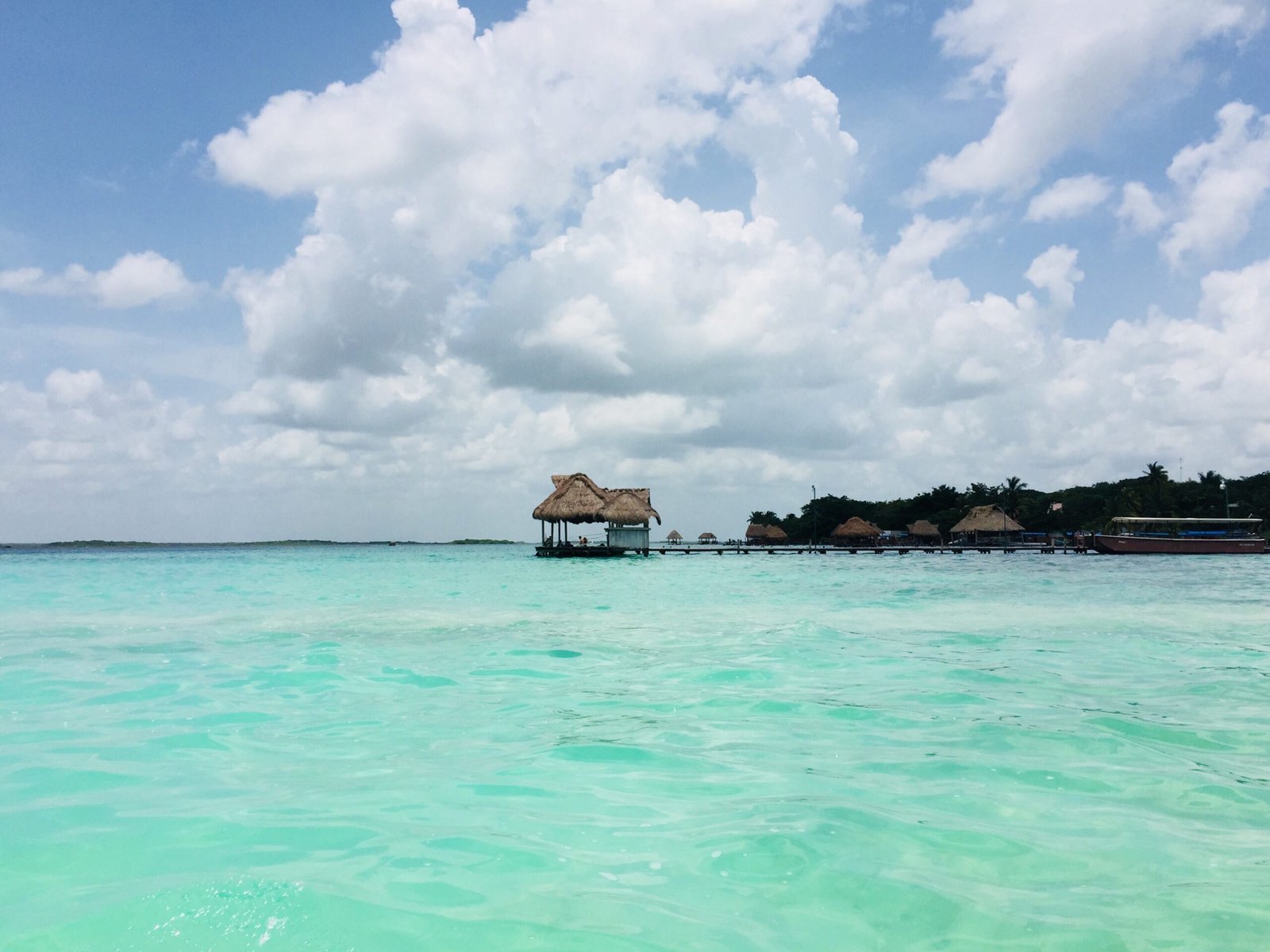 Tranquil turquoise waters and thatched roof structure at Bacalar Lagoon